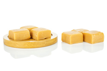 Group of six whole sweet golden caramel candy on bamboo coaster isolated on white background