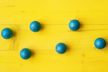 Blue Christmas balls on yellow wooden background. Xmas and New Year concept
