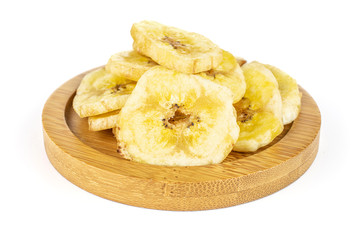 Lot of slices of sweet yellow dry banana on bamboo coaster isolated on white background