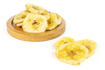 Lot of slices of sweet yellow dry banana three are aside and the rest is on bamboo coaster isolated on white background