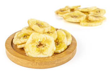 Lot of slices of sweet yellow dry banana on bamboo coaster isolated on white background