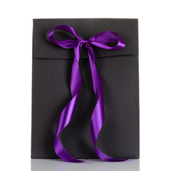 Black paper gift bag with purple bow isolated on white background