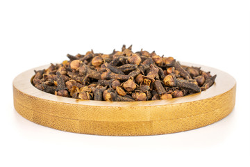 Lot of whole dry brown clove on bamboo coaster isolated on white background