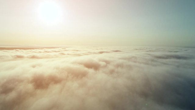 High aerial view of the large shiny sun over fluffy golden clouds. 4K.