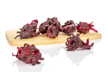 Lot of whole sweet red candied hibiscus on bamboo cutting board isolated on white background