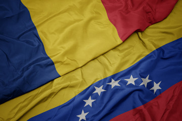 waving colorful flag of venezuela and national flag of romania.