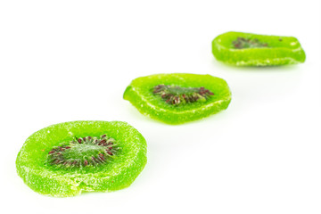 Group of three slices of sweet green candied kiwifruit placed diagonally isolated on white background
