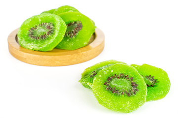 Group of seven slices of sweet green candied kiwifruit on bamboo coaster isolated on white...