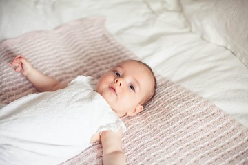 Little cute girl 3 months old is lying on the bed. Baby. Children bedroom.