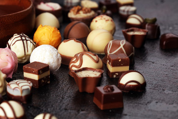 a lot of variety chocolate pralines, belgian confectionery gourmet chocolate on rustic dark background