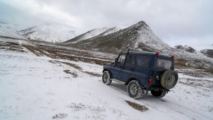 Off-road car rides on a snowy road in a valley among the mountains near the intersection of the Arctic circle and the 180th meridian. Chukotka, Russia. Expeditions, arctic travel and extreme tourism.