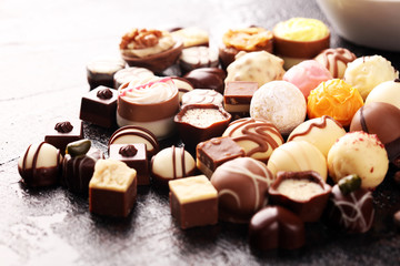 a lot of variety chocolate pralines, belgian confectionery gourmet chocolate on rustic dark background