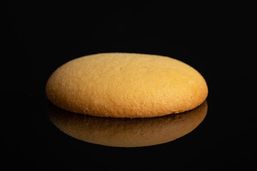 One whole sweet golden sponge biscuit isolated on black glass