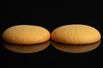 Group of two whole sweet golden sponge biscuit isolated on black glass