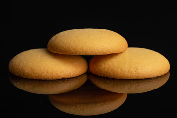Fototapeta na wymiar Group of three whole sweet golden sponge biscuit isolated on black glass