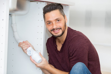 portrait of man fitting waste pipe on sink