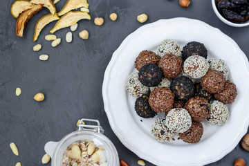 Energy balls of nuts, oatmeal and dried fruits on a plate on dark background, horizontal orientation
