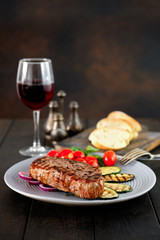 Grilled beef steak and zucchini served with fresh tomato cherry and basil and a glass of red wine