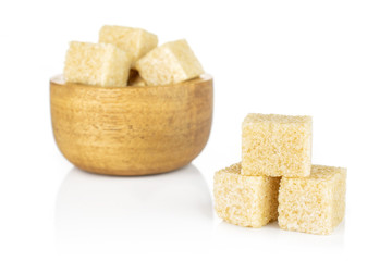 Lot of whole sweet brown sugar cube three are aside and the rest is in tiny wooden bowl isolated on white background