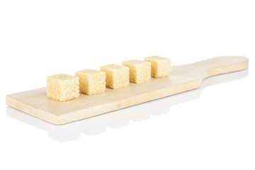 Group of five whole sweet brown sugar cube on small wooden cutting board isolated on white background