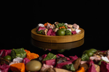 Lot of whole sweet chocolate stone on bamboo coaster isolated on black glass