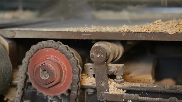 A small wood processing workshop. Private sawmill. The jointer machine processes a thick board. Side view. The video contains sound.