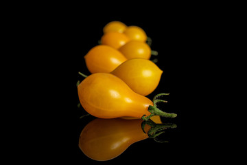 Group of seven whole fresh yellow pear tomato isolated on black glass