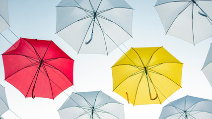 Umbrellas against the blue sky. White, yellow and red umbrella