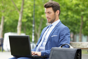 stylish man with laptop on bench