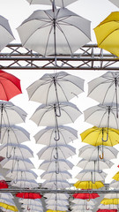 Umbrellas against the blue sky. White, yellow and red umbrella