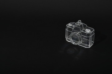 Llavero de cámara fotográfica transparente en fondo negro con reflejo
