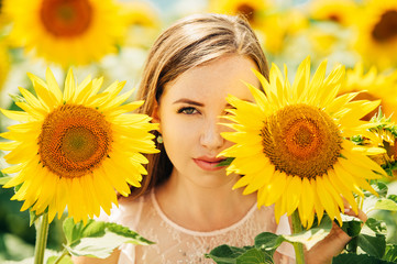 Outdoor portrait of beautiful young woman with sunflowers, health and lifestyle, girl hiding behind flowers