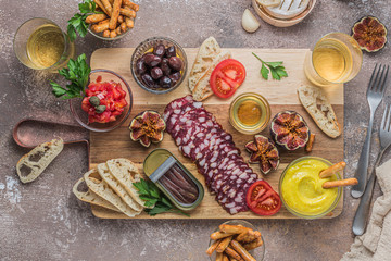Salami, cheese, anchoves, bread and alioli dip on wooden board, flat lay