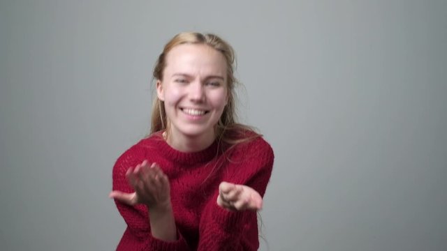 Blonde caucasian woman in red sweater pointing and laughing at you