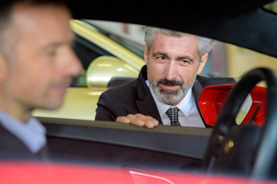 car dealer talking with the client inside the car