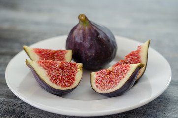 Ripe fig fruits are on the white plate.