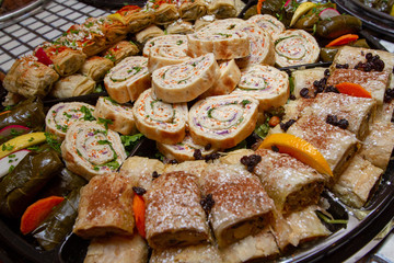 Mediterranean filo dough specialties, including chicken cilicia, dolmas, and Levant sandwiches on a platter as seen from above. 
