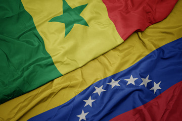 waving colorful flag of venezuela and national flag of senegal.