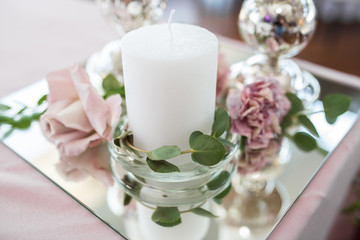 The wedding table setting for the newlyweds is decorated with fresh flowers of carnation, rose, anthurium and eucalyptus leaves. Silver candlesticks, white candles. Wedding floristry. Closeup details