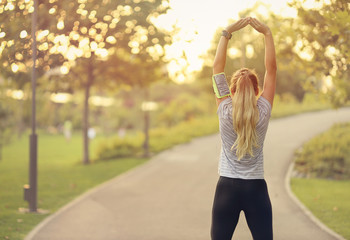 Fit young woman running in park - Attractive blonde female doing stretching exercises outdoors - healthy lifestyle concept