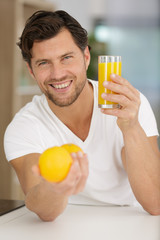 Fototapeta premium man holding orange juice and smiling in the kitchen