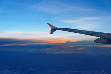 Airplane wing against sky at sunset