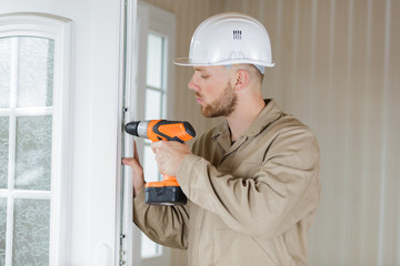 man drilling a hole in a door in a room