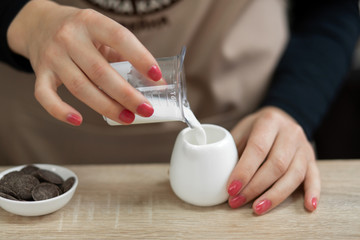 Barista in an apron pours milk into a cup. Barista work in a coffee shop