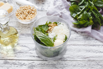 The process of making pesto sauce in a blender from cheese, pine nuts, olive oil, basil, garlic on...