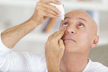 man dripping eye drops with hand