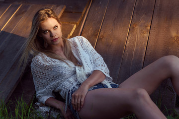 Obraz premium Countryside style woman, lying on wooden boards. Warm sunset sunlight and shadow.