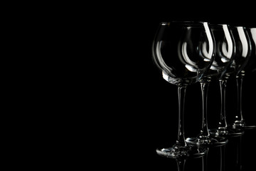 Set of empty wine glasses on black background. Space for text