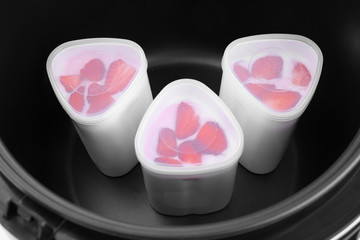 Cups of homemade strawberry yogurt in modern multi cooker, closeup view