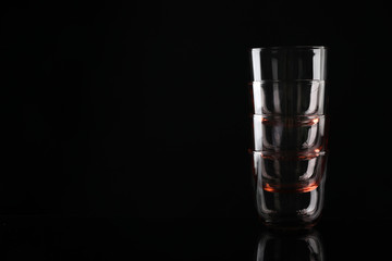 Stack of empty colorful whiskey glasses on black background, space for text